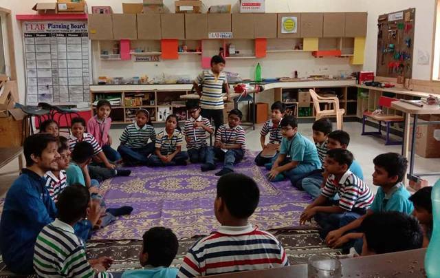 Children sitting in a circle in a T-LAB for a sharing meeting
