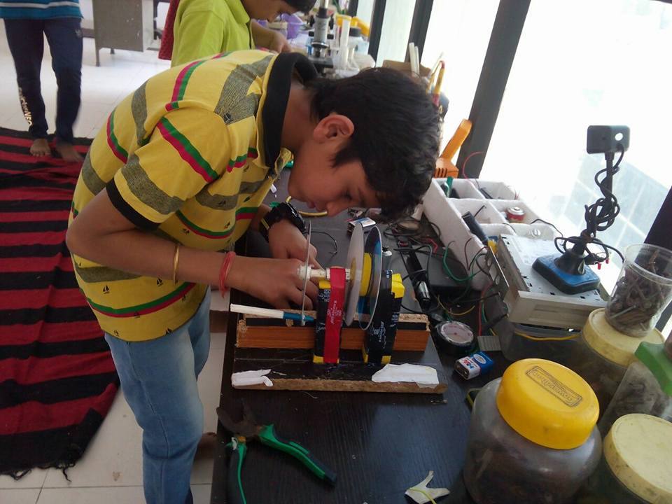 A child fitting a motor at a workbench during a tinkering workshop