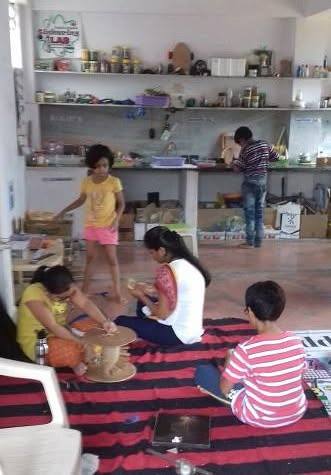 Children making things in a home tinkering space with open shelves of materials