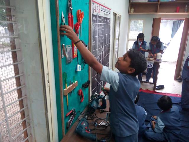 A boy at a wall of tools during a workshop